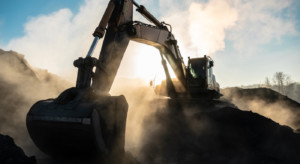 Yellow big excavator in the coal mine, loads the breed, with the bright sun and nice blue sky in the background. Mining truck mining machinery. Technique in coal mine.