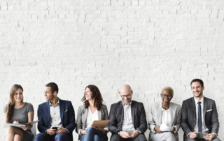 A row of men and women in suits, talking and smiling