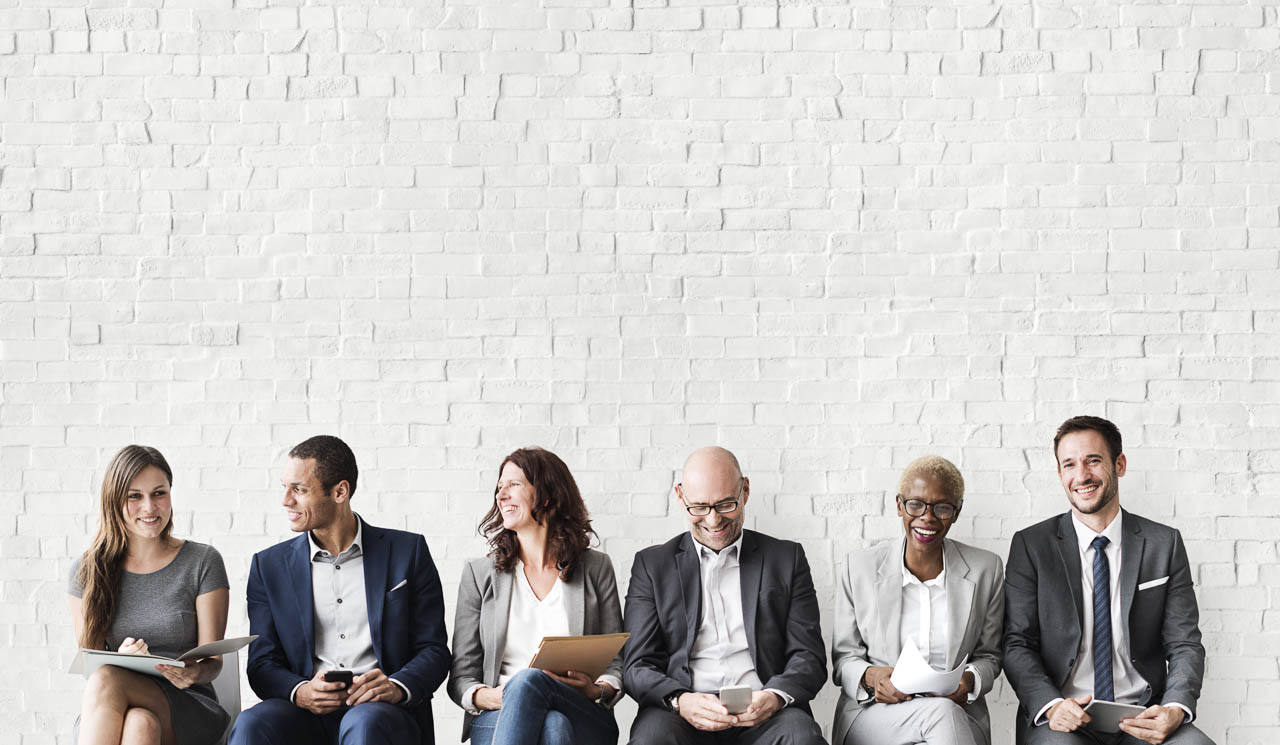 A row of men and women in suits, talking and smiling
